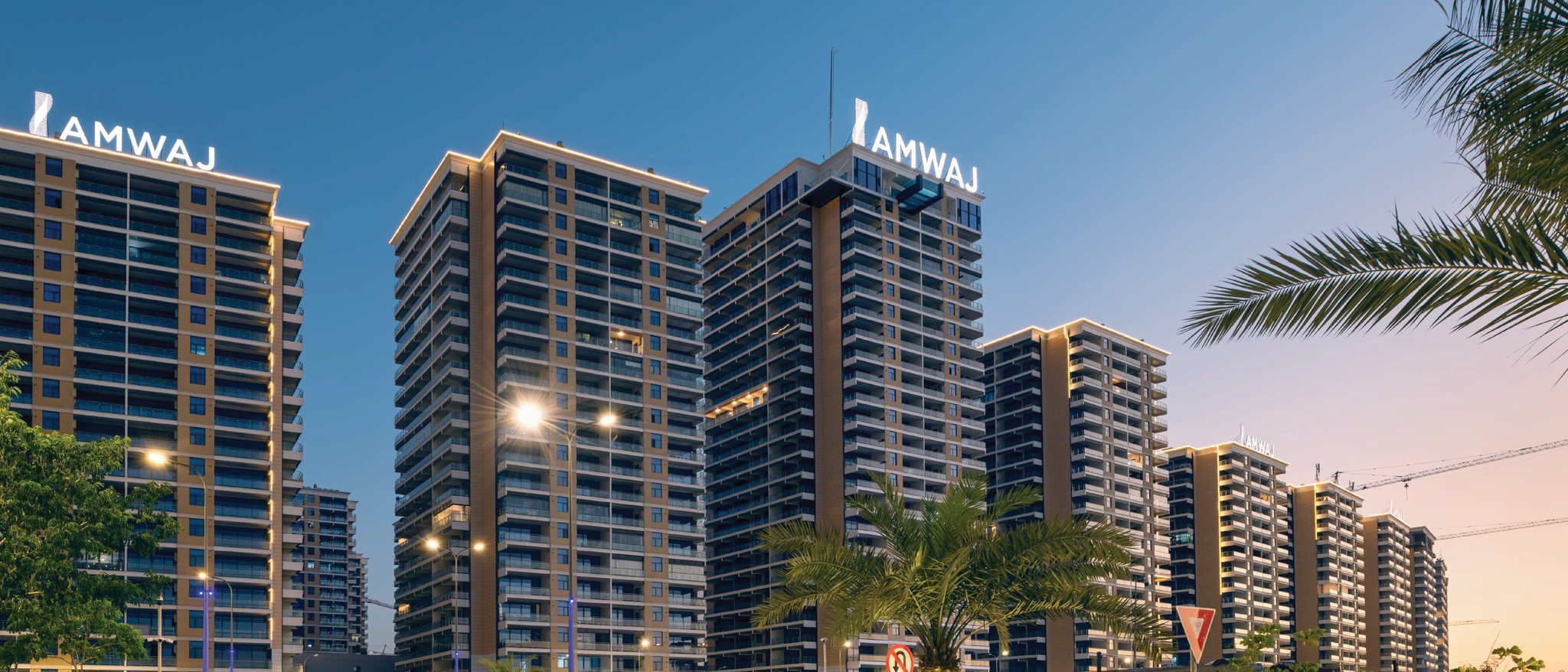 Iraq Gate – The Boulevard: residential towers at dusk with Amwaj rooftop signage